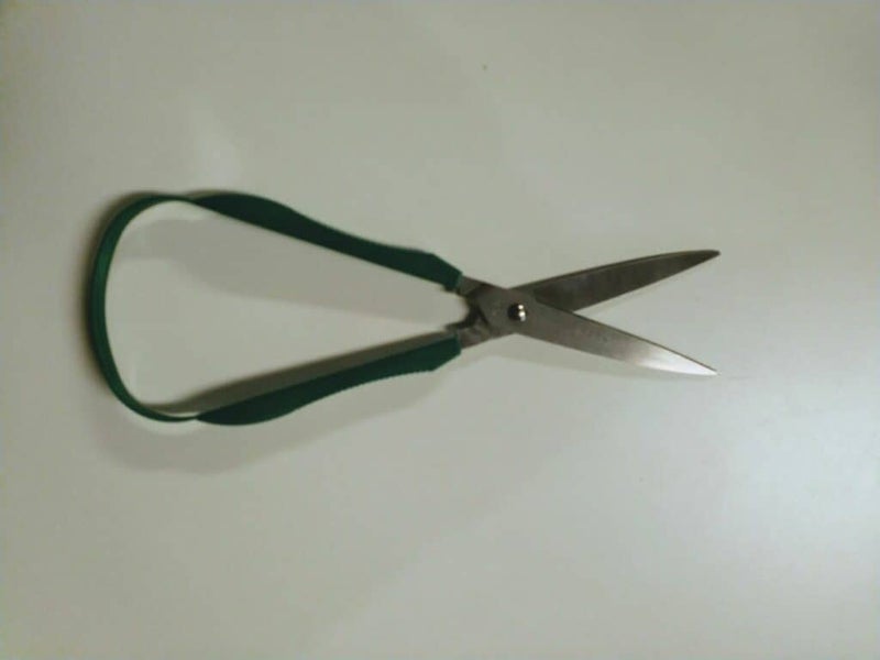 Sakset palautusmekanismilla